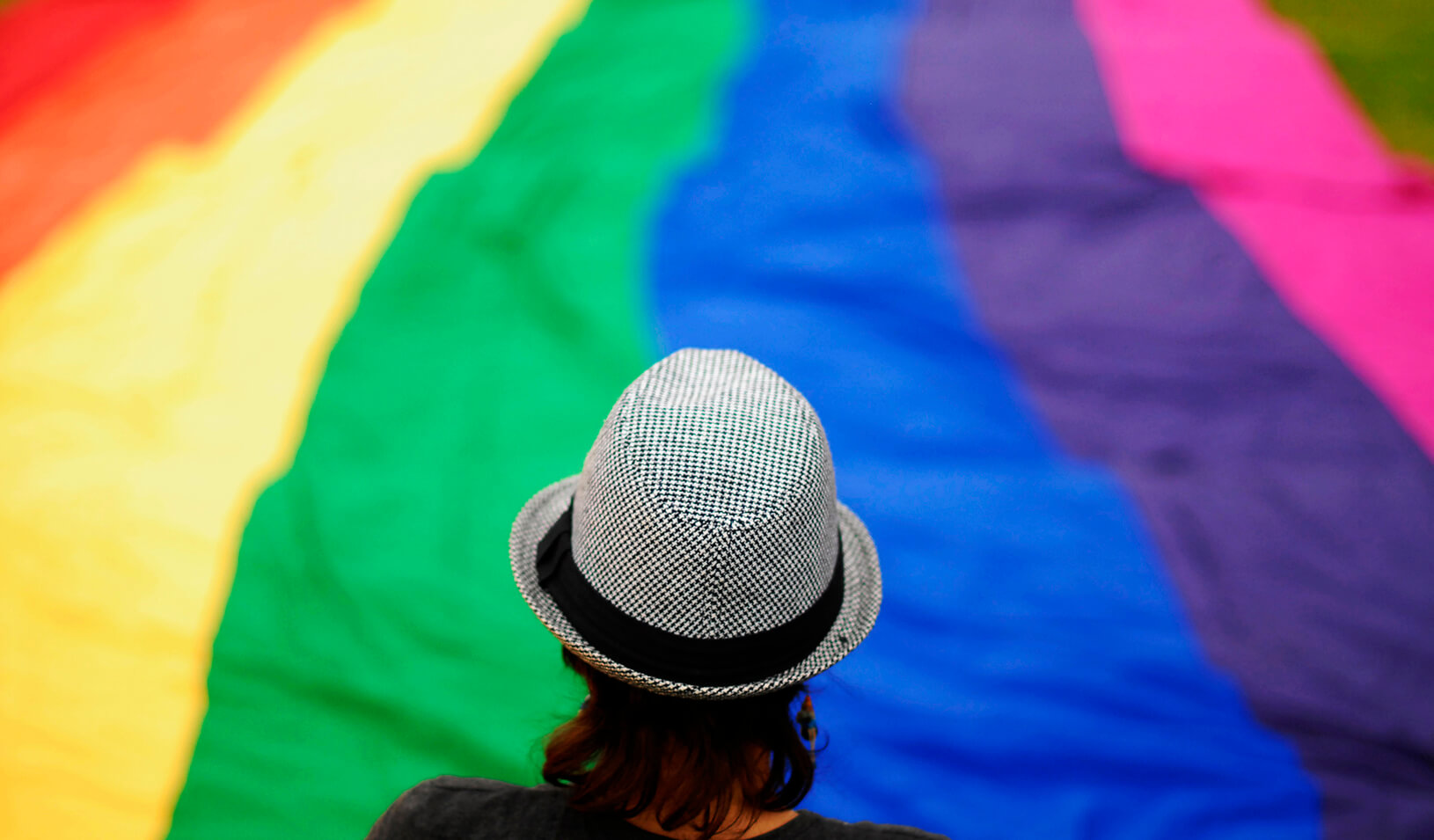 A transgender person overlooks a large rainbow banner  | Reuters/Ulises Rodriguez