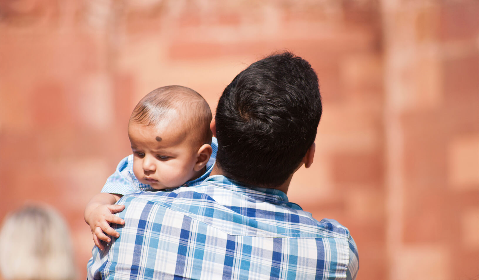 A father holding a baby | iStock/RobertoMussi
