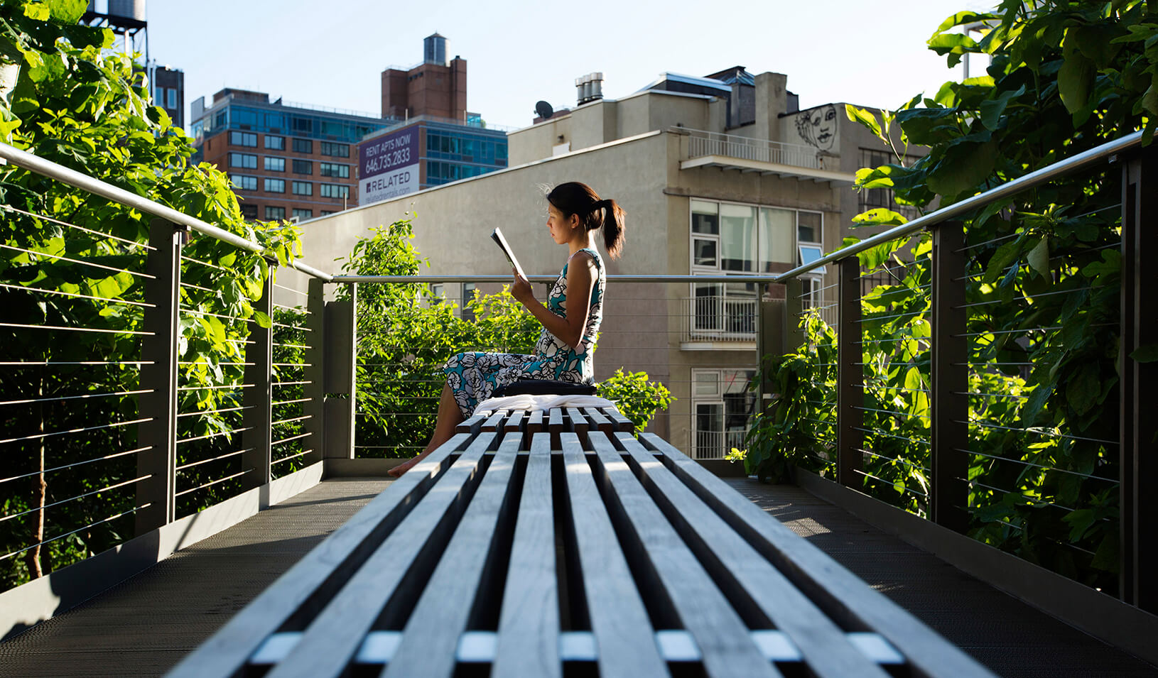 A woman uses the late afternoon sun to read while sitting on the High Line park in New York | Reuters/Lucas Jackson