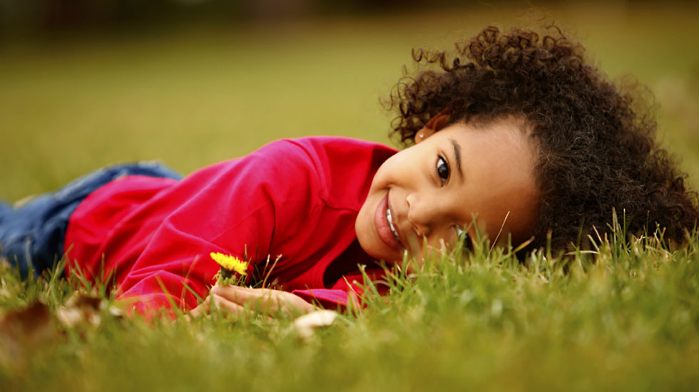 Young child laying on the green grass