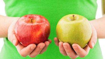 Person holding a red apple in one hand and green apple in other hand
