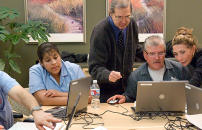 Male and female instructor teaching computer literacy class to men and women