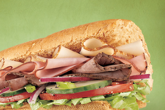 Subway Sandwich with turkey, hame and roast beef on top of fresh vegetables. 