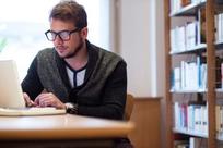 Young man using laptop and studying in library
