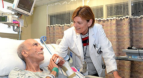 Image of a female doctor talking w with a male patient in a hospital bed