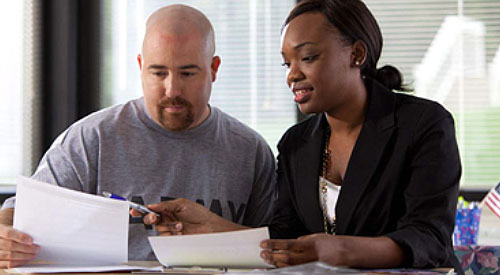 Image of a man and a women both looking at and discussing a piece of paper.