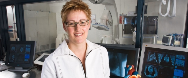 Female researcher next to a model of a heart