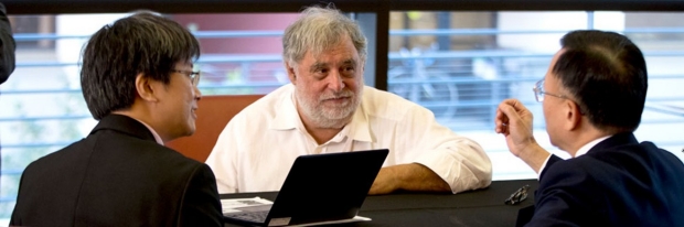 Three men at desk talking