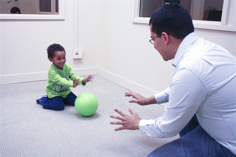 Researcher rolling a ball to a toddler