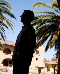 photo of man in shadow with sunny campus in background