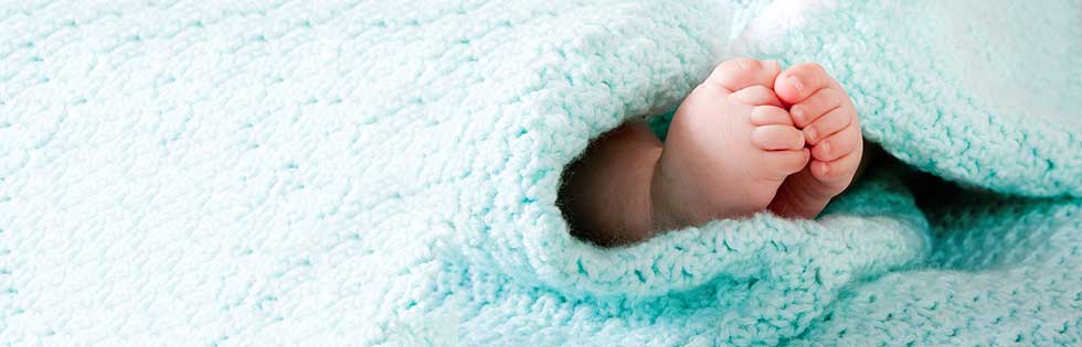 baby feet wrapped in a fuzzy blue blanket