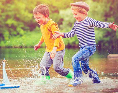 Boys splashing in the water with a sailboat