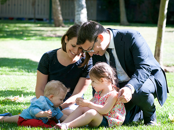 Faculty member and wife with two young children sitting on lawn