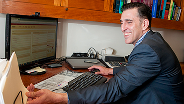 Male staff member pulling a file folder while working on computer