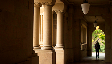 Person walking through dim corridor past columns