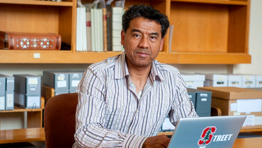 Hispanic or Middle Eastern male staffer working on laptop in library