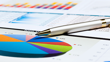 Pen on report document with pie chart and bar graph