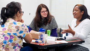 Three diverse female staff talking to each other in classroom