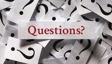 Slips of paper with question smarks, and sign in middle with "Questions?" in red