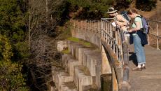 A female docent and participant pause in their hike to peer over Searsville Dam at Jasper Ridge Biological Preserve.