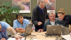 Male and female instructor teaching computer literacy class to men and women