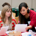 Female Welcome Center staffer helps a new hire with her laptop during orientation