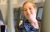 Young female staffer smiling while sitting in commuter train.