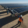 Workers starting a robot on a solar panel.