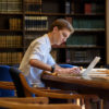 Undergraduate Anatole Schneider examing Italian newspapers from 1947-48 at the Hoover Library reading room.