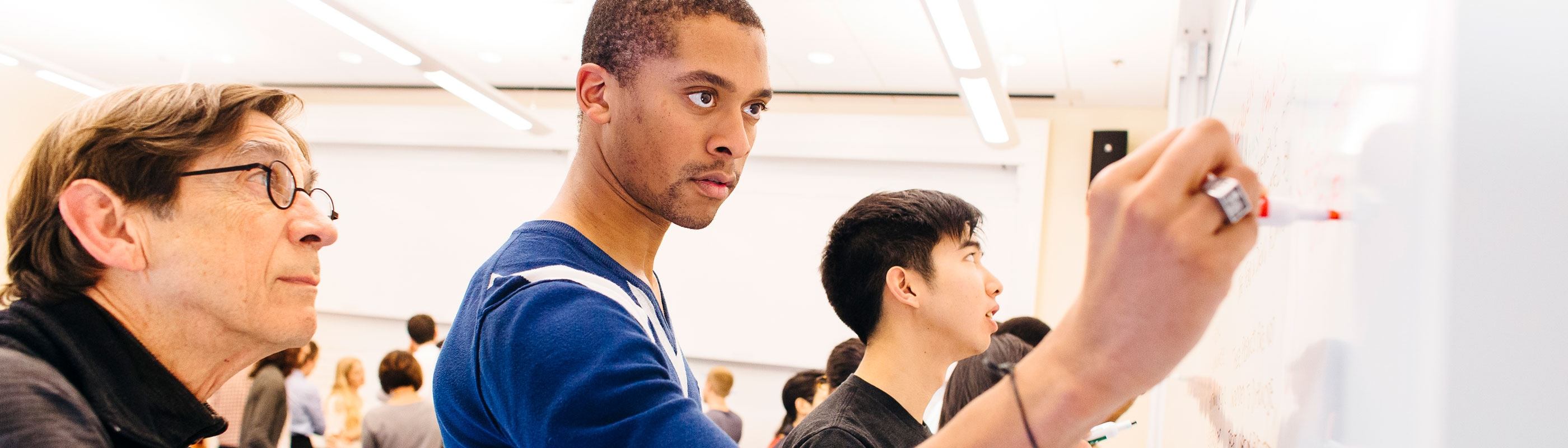 Stanford GSB students write on the white board.