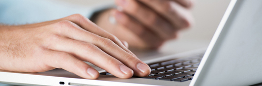 Person working on a laptop while accessing their smartphone.