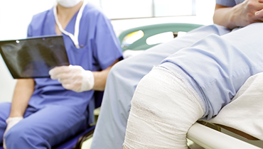 Close up of person with knee injury next to medical staff with X-ray in hand