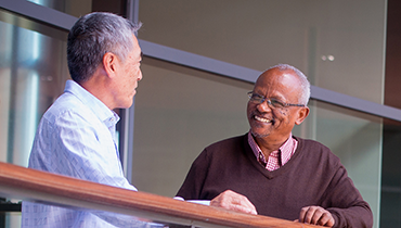 Two male colleagues chatting on a balcony