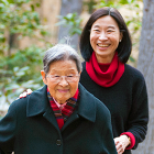 Smiling Asian female staffer walking with her cheerful elderly mother.