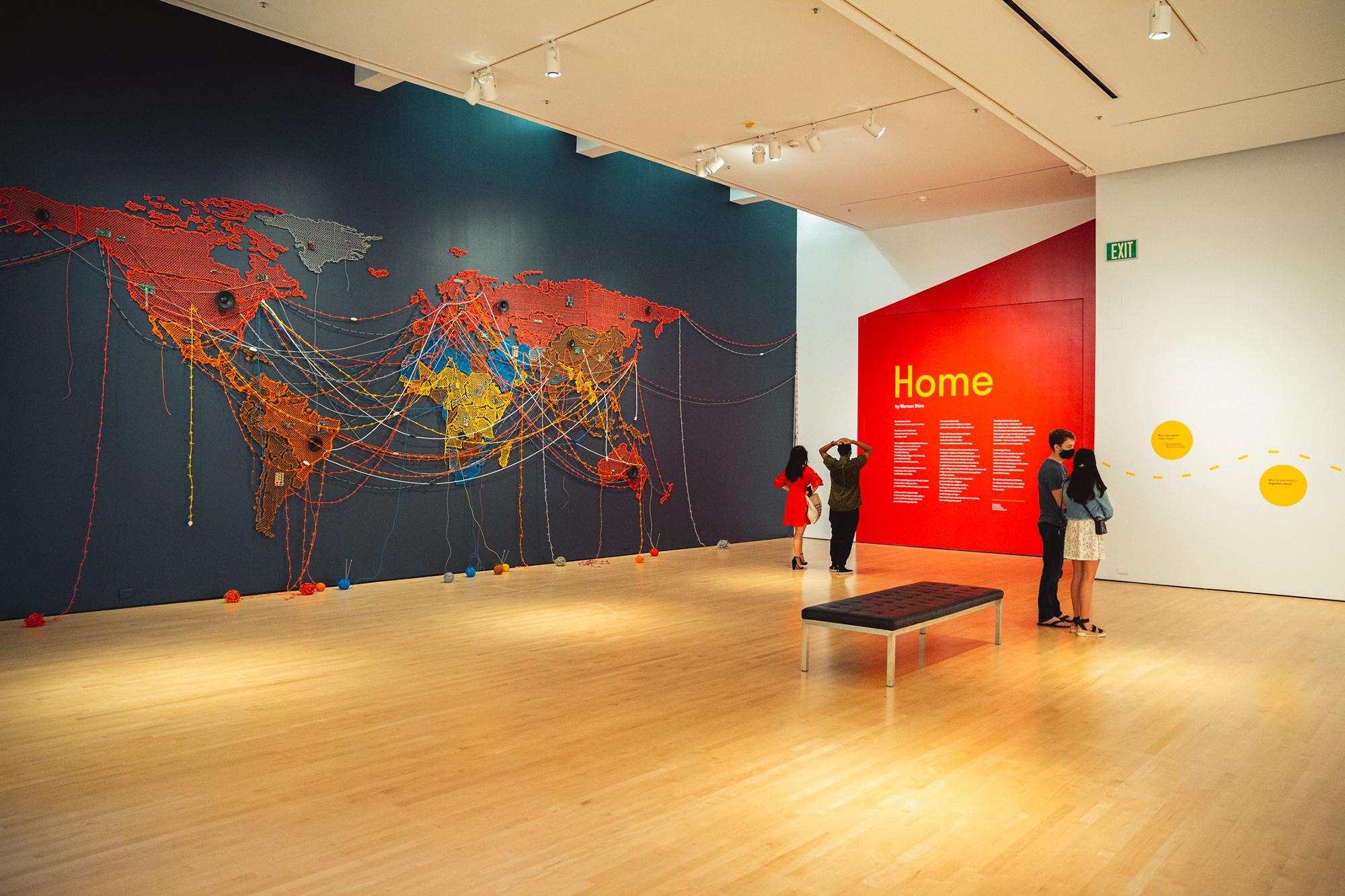 Visitors walk past Reena Saini Kallat's piece "Woven Chronicle" (2011-2019) in the temporary exhibition "When Home Won’t Let You Stay: Migration through Contemporary Art" in the Cantor Arts Center at Stanford University. Courtesy Andrew Brodhead/Stanford University.