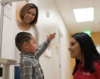 A young patient at Stanford Children's Health in clinic having his height and weight measured.