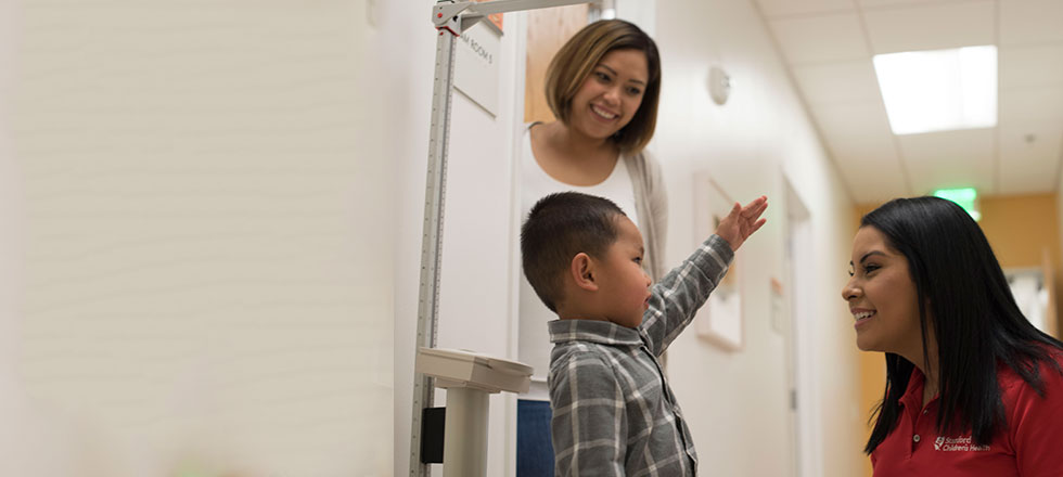 A young patient at Stanford Children's Health in clinic having his height and weight measured.