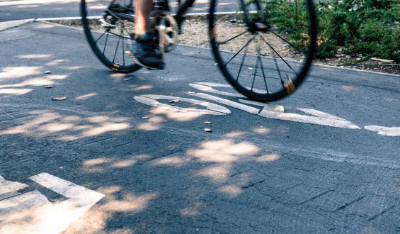 lower part of bike (legs and wheels) with bike lane sign