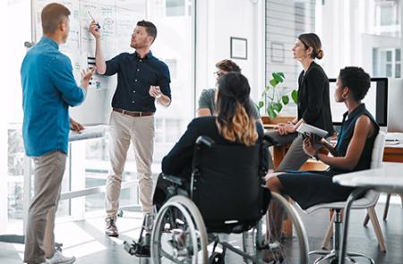 Group of coworkers observing a team member at a whiteboard