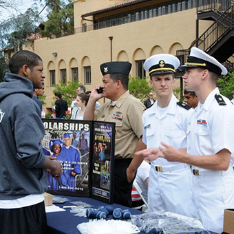 Student talking to military recruiters at an outside fair