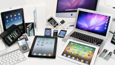 Various Apple products displayed on table: tablets, laptops, phones, etc.