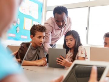 Picture of teacher with students looking at an ipad