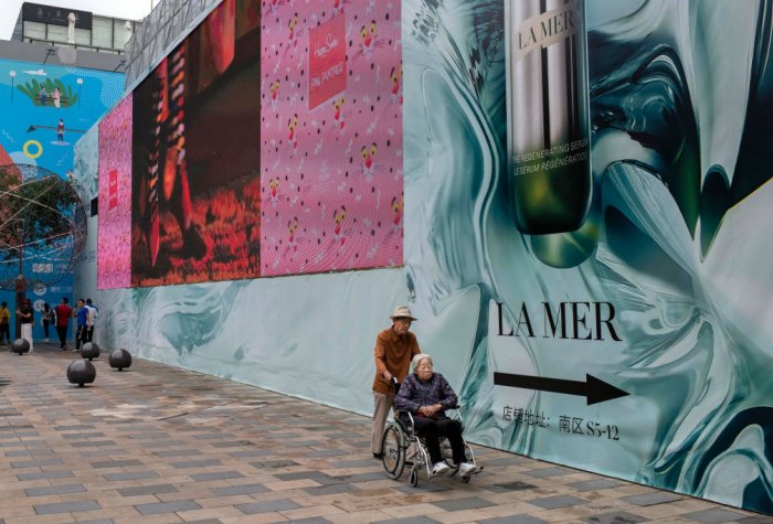 n elderly Chinese man pushes an elderly woman in a wheelchair through a local shopping mall in Beijing, China