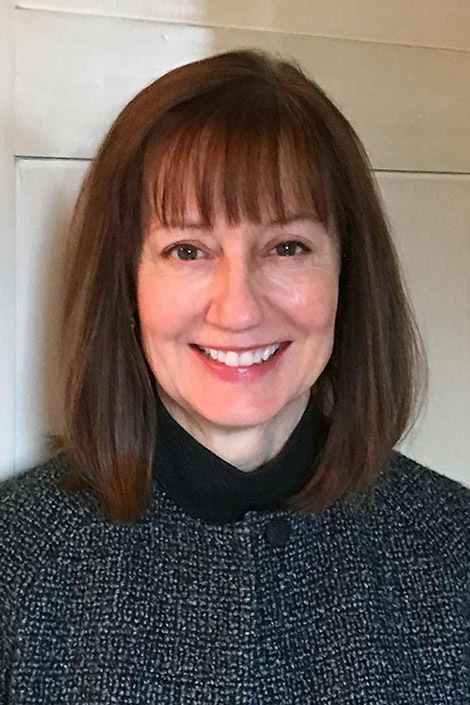 A headshot of Roberta Denning standing in front of a white wall.