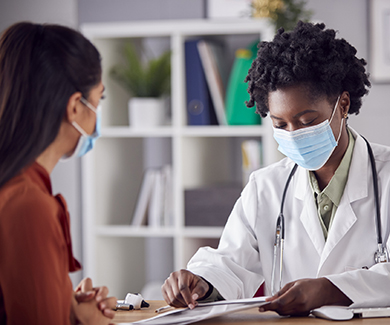 Masked patient consults with physician.